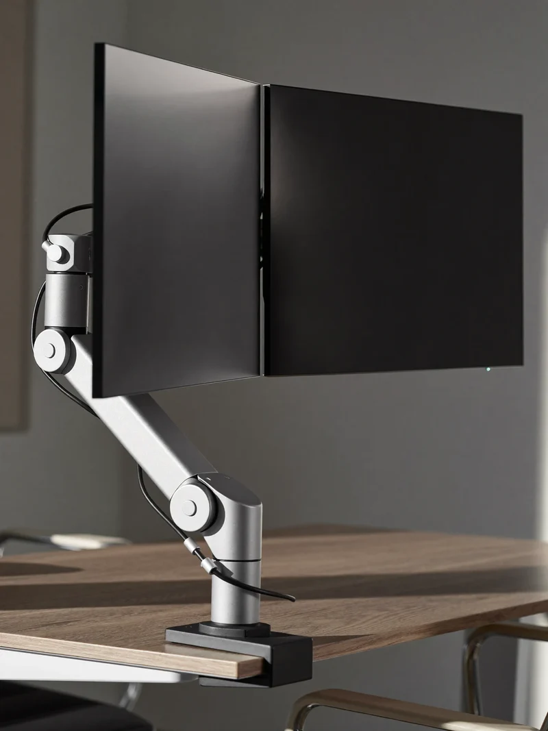 Bras double fixé au bord du bureau, portant deux écrans éteints.